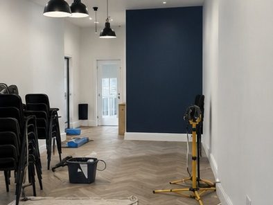 A finished navy feature wall in a hall, stacked chairs to one side and sheets still on the floor