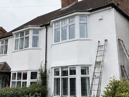 A white rendered semi detached house with ladders against the front elevation