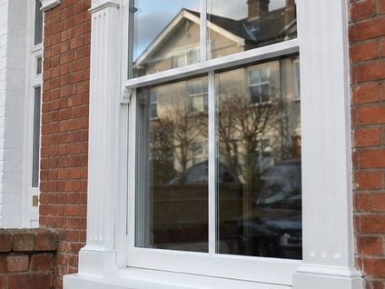 A white painted sash window in a brick elevation, the woodwork freshly coated